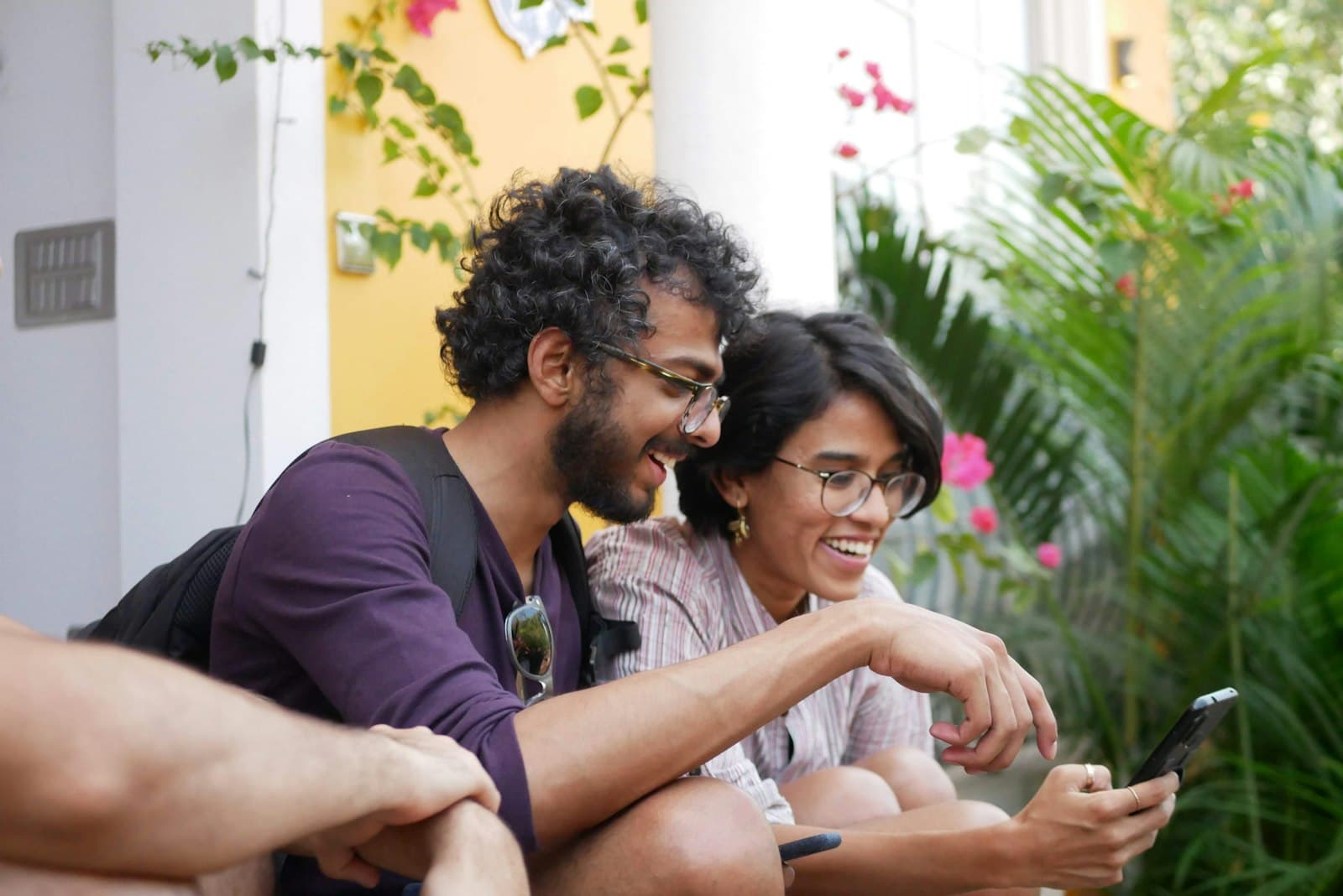 Two people laughing while looking at a smartphone
